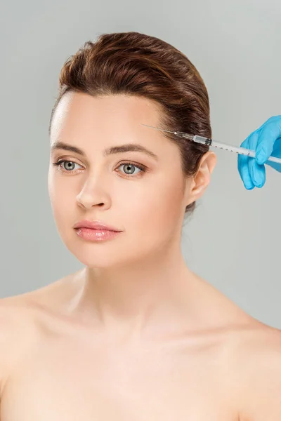 Visão recortada de cosmetologista segurando seringa perto do rosto de mulher nua isolada em cinza — Fotografia de Stock