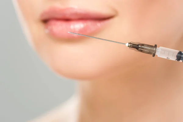 Selective focus of syringe near face of woman isolated on grey — Stock Photo