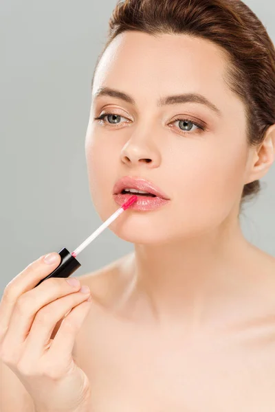 Attractive naked woman applying lip gloss on lips isolated on grey — Stock Photo