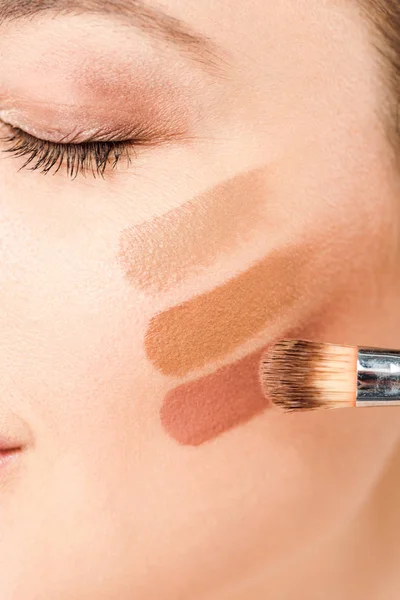 Vista recortada de la mujer con los ojos cerrados y sombra de ojos paleta marrón en la cara - foto de stock