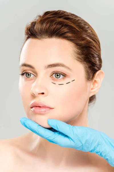 Cropped view of plastic surgeon touching face of pretty woman with marked face isolated on grey — Stock Photo