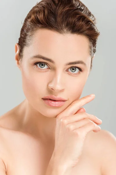 Serious naked woman looking at camera and touching face isolated on grey — Stock Photo