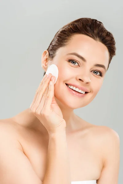 Mulher positiva segurando almofada de algodão perto do rosto e sorrindo isolado no cinza — Fotografia de Stock