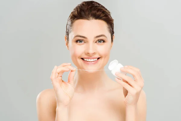 Cheerful naked woman holding dental floss and smiling isolated on grey — Stock Photo