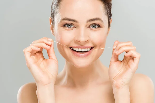 Happy naked woman flossing teeth with dental floss isolated on grey — Stock Photo