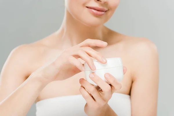 Foyer sélectif de la femme tenant le récipient avec crème visage isolé sur gris — Photo de stock