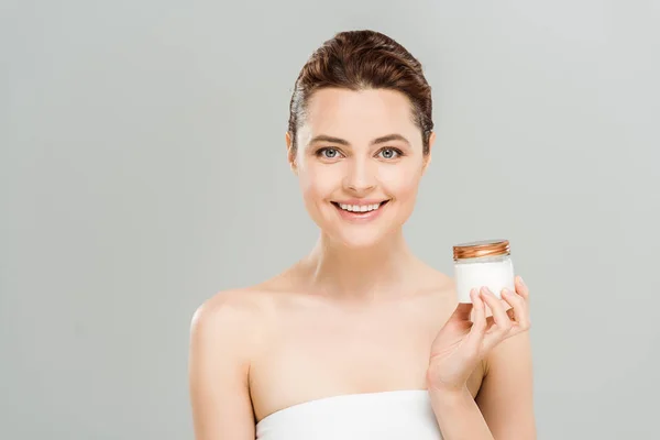 Happy woman holding container with face cream isolated on grey — Stock Photo