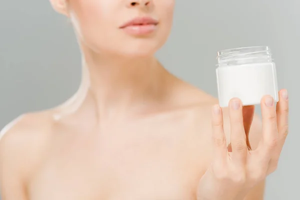 Abgeschnittene Ansicht einer nackten Frau, die Behälter mit kosmetischer Creme auf grau isoliert hält — Stockfoto