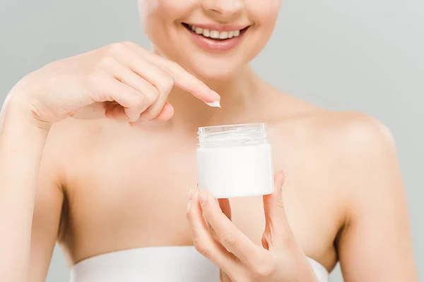 Cropped view of smiling woman holding container with face cream isolated on grey — Stock Photo