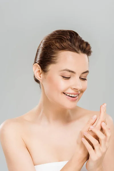 Cheerful woman looking at hands and smiling isolated on grey — Stock Photo