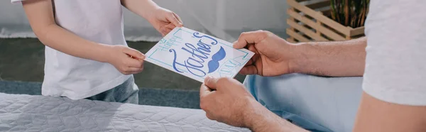 Plano panorámico del hijo regalando tarjetas de felicitación del día de los padres a papá - foto de stock