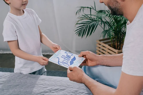 Tiro cortado de filho presenteando pais dia cartão de saudação ao papai — Fotografia de Stock