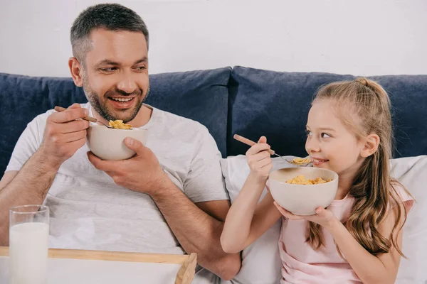 Pai alegre com filha adorável tomando café da manhã na cama no dia dos pais juntos — Fotografia de Stock