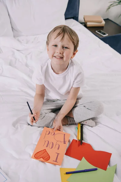 Entzückendes Kind, das Vatertags-Grußkarte mit der Aufschrift I love you Papa und Herzsymbol macht, während es in die Kamera lächelt — Stockfoto
