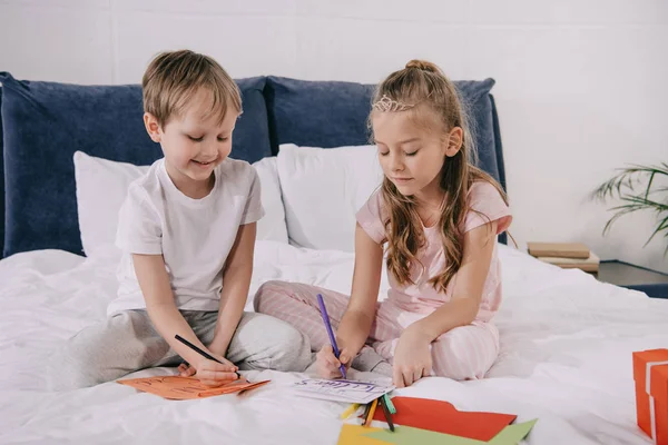 Cute kids making fathers day greeting cars while sitting on bedding at home — Stock Photo