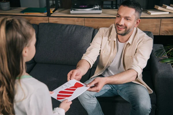 Bambino che presenta il biglietto di auguri del giorno dei padri con legame disegnato al padre felice — Foto stock