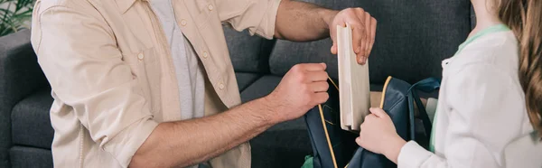 Panoramaaufnahme von Vater hilft Tochter Bücher in Rucksack zu packen — Stockfoto