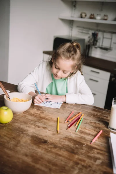 Adorable child drawing fathers day greeting card while sitting at wooden table — Stock Photo