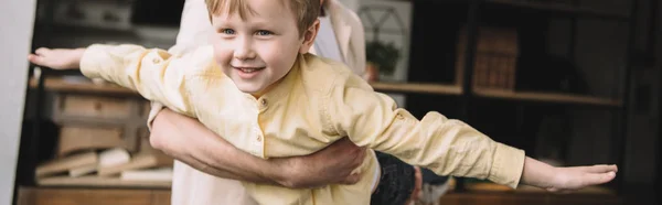 Colpo panoramico di uomo che si diverte con adorabile figlio sorridente a casa — Foto stock