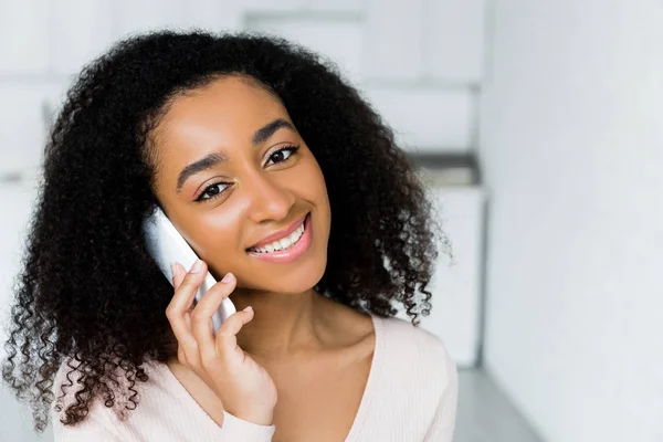 Retrato de mujer afroamericana hablando en smartphone y mirando a la cámara - foto de stock