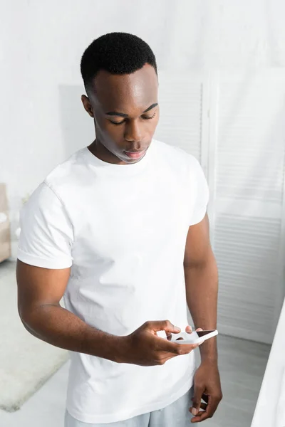 Hochblickaufnahme eines afrikanisch-amerikanischen Mannes mit Smartphone in der Hand — Stockfoto