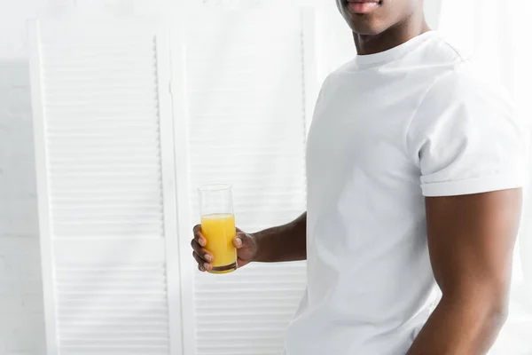 Vista cortada do homem americano africano segurando vidro de suco na mão — Fotografia de Stock