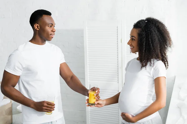 African american man giving glass with orange juice to pregnant girlfriend — Stock Photo