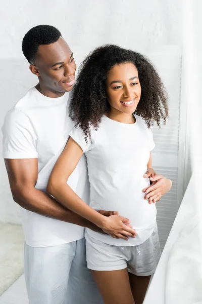 Heureux afro-américain homme câlin avec femme enceinte — Photo de stock