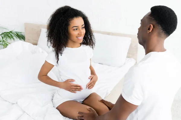 Vista de ángulo alto de la mujer afroamericana feliz y embarazada mirando novio - foto de stock