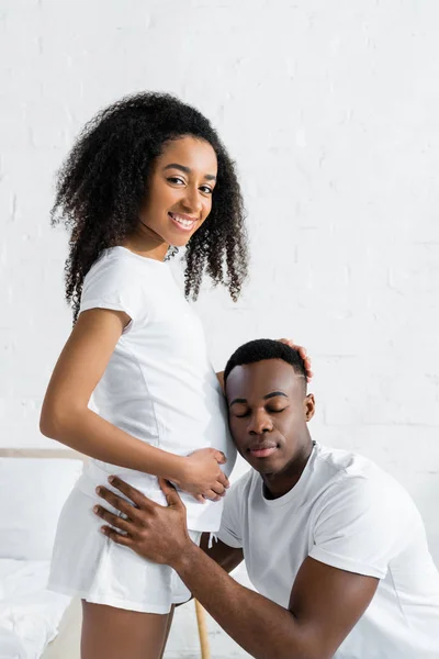 Афроамериканський чоловік слухає животик вагітної дружини — стокове фото