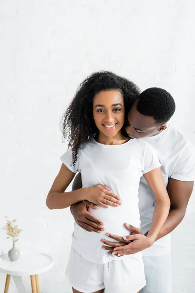 Calme afro-américain homme câlin avec femme enceinte — Photo de stock