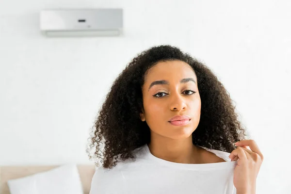 Retrato de afro-americano chateado mulher em pé no quarto com ar condicionado e olhando para a câmera — Fotografia de Stock