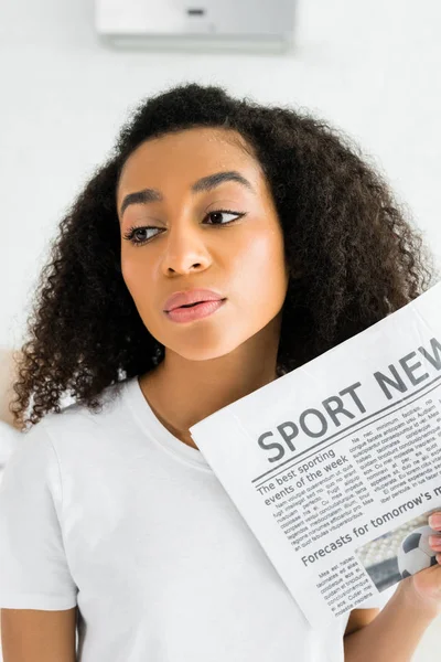 Femme afro-américaine en sueur avec journal à la main, détournant les yeux — Photo de stock