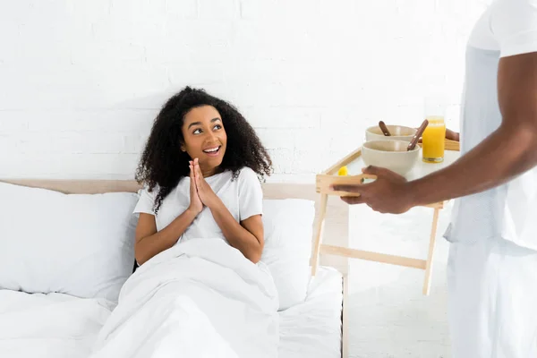 Afro-américaine femme regardant petit ami avec plateau de petit déjeuner dans les mains — Photo de stock