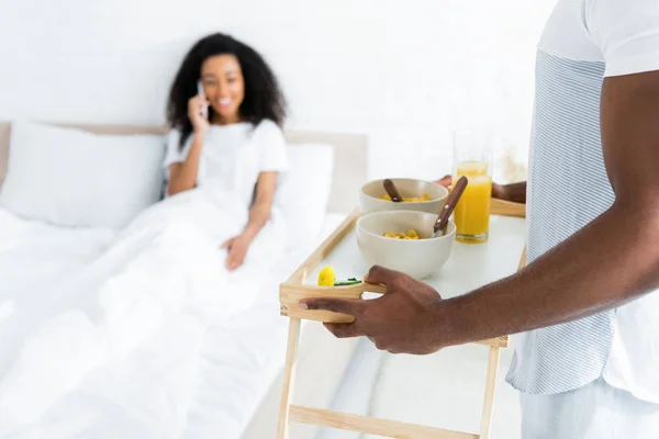 Selective focus of african american man holding try with breakfast, on smiling girlfriend background — Stock Photo