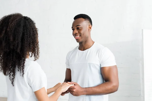 Happy african american holding hands with girlfriend, looking at her eyes — Stock Photo