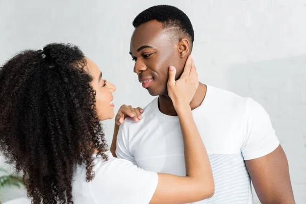 Alegre afroamericana mujer mirando guapo novio, de pie en blanco habitación - foto de stock