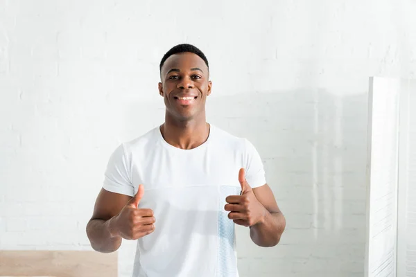 Vista frontal do homem americano africano feliz mostrando polegares para cima, olhando para a câmera — Fotografia de Stock