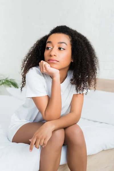 Calma donna afro-americana seduta sul letto, distogliendo lo sguardo — Foto stock