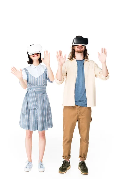 Vista completa de dos personas con auriculares VR levantando las manos en el aire aislado en blanco - foto de stock
