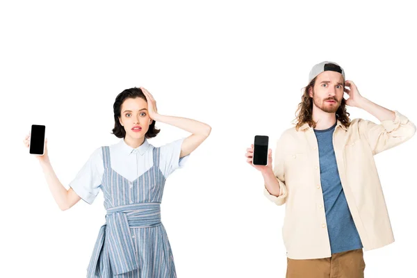 Confundido joven y niña sosteniendo teléfonos inteligentes en manos aisladas en blanco - foto de stock
