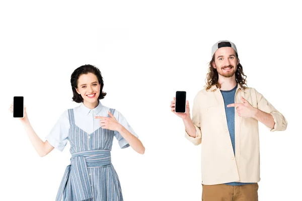 Jeune couple tenant smartphones dans les mains et pointant avec les doigts sur les téléphones isolés sur blanc — Photo de stock