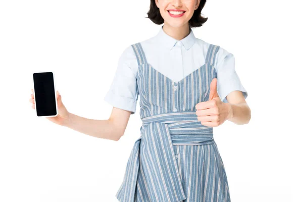 Vista recortada de la niña sosteniendo el teléfono inteligente en la mano y mostrando el pulgar hacia arriba aislado en blanco - foto de stock