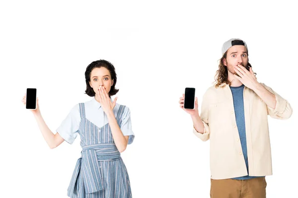 Sorprendido joven hombre y chica sosteniendo teléfonos inteligentes en manos aisladas en blanco - foto de stock