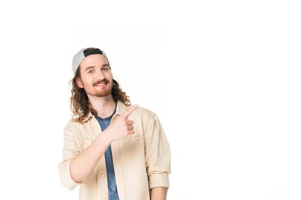 Bel giovane uomo che punta con il dito lontano e guardando la fotocamera isolata sul bianco — Foto stock