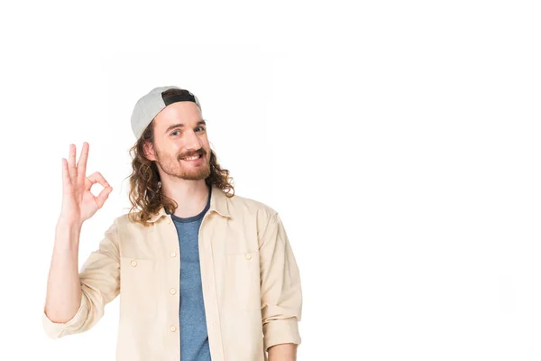 Schöner junger Mann zeigt ok Zeichen vor der Kamera isoliert auf weiß — Stockfoto