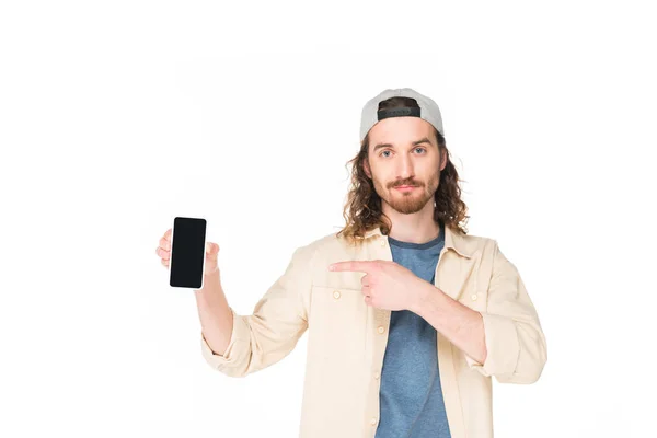 Молодий чоловік тримає і вказує пальцем на смартфон ізольовано на білому — стокове фото