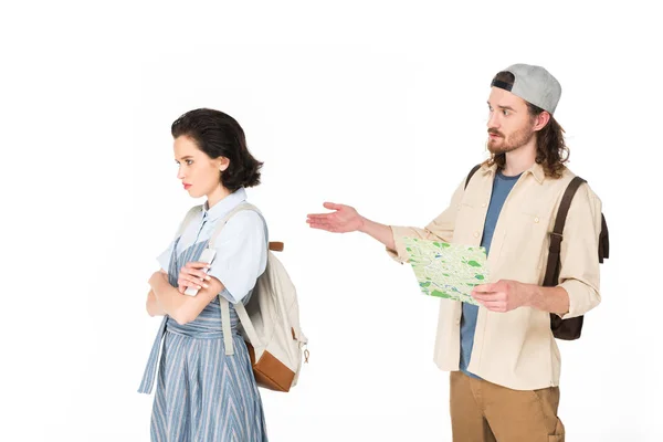 Joven hombre sosteniendo mapa en las manos, tratando de hablar con chica ofendida aislado en blanco - foto de stock