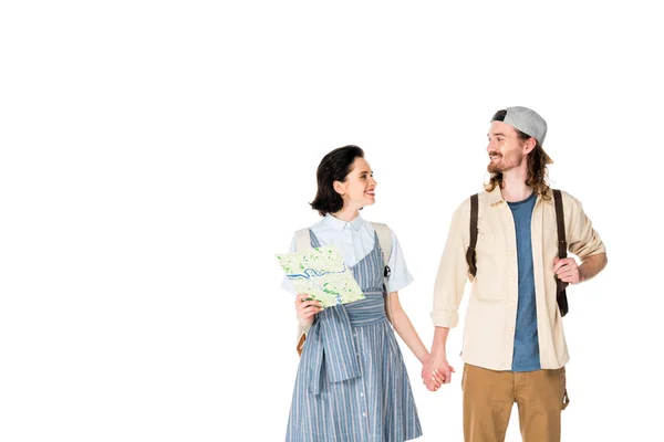 Вид спереди девушки, держащей карту, и молодого человека, держащегося за руки и улыбающегося изолированно на белом — стоковое фото