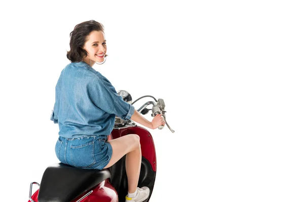 Chica mirando a la cámara y sentado en scooter rojo aislado en blanco - foto de stock